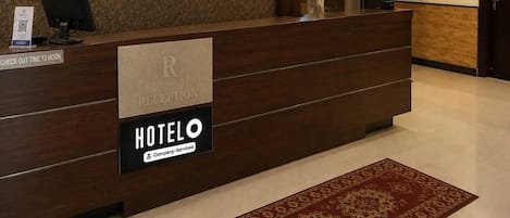 A hotel reception desk with a clock, a no-smoking sign, and a check-out time sign.