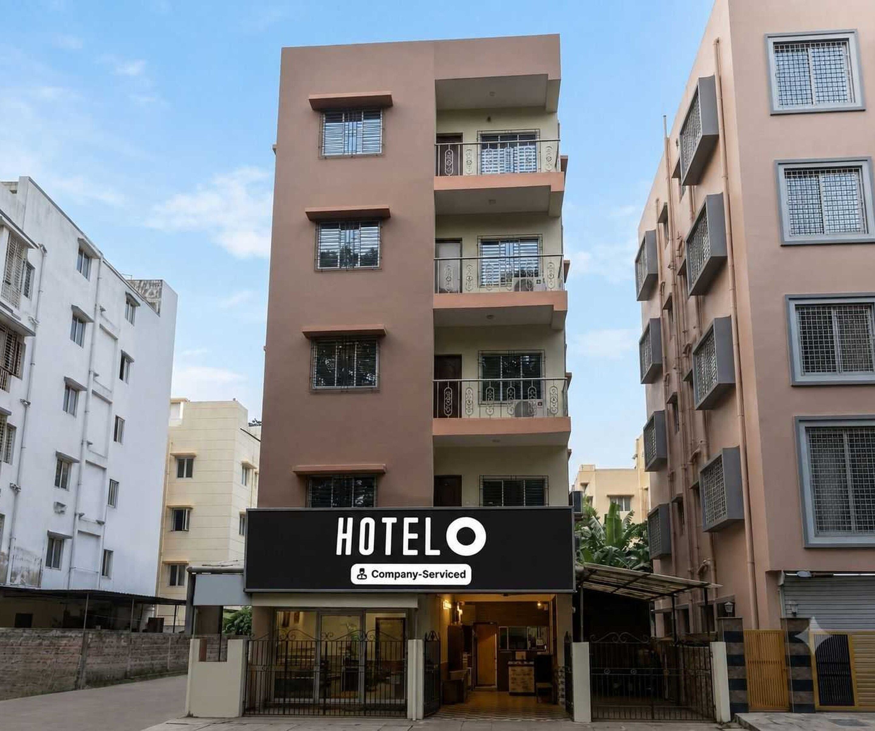 A multi-story hotel building with balconies and a sign indicating it is company-serviced.