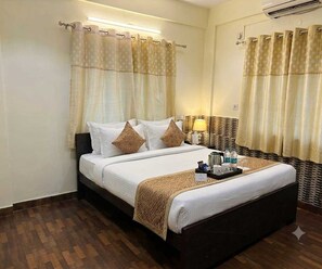 Una habitación de hotel con una cama, una mesita de noche con lámpara y una bandeja con artículos de aseo.