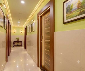 Pasillo de hotel con una puerta de madera marcada '302', una obra de arte enmarcada en la pared y una pequeña mesa con una planta.