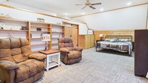 A cozy room with a bed, two armchairs, a small table, and a ceiling fan. - UP Getaway - Pictured Rocks and Hiawatha National Forest awaits you! (Munising)