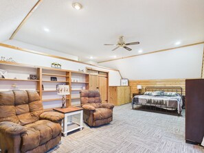 A cozy room with a bed, two armchairs, a small table, and a ceiling fan. - UP Getaway - Pictured Rocks and Hiawatha National Forest awaits you! (Munising)
