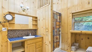 A wooden cabin bathroom with a sink, mirror, and shower curtain. - UP Getaway - Pictured Rocks and Hiawatha National Forest awaits you! (Munising)