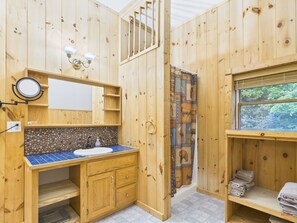 A wooden cabin bathroom with a sink, mirror, and shower curtain. - UP Getaway - Pictured Rocks and Hiawatha National Forest awaits you! (Munising)