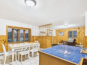 A room with a dining table, chairs, a wooden partition, and a blue-tiled counter. - UP Getaway - Pictured Rocks and Hiawatha National Forest awaits you! (Munising)