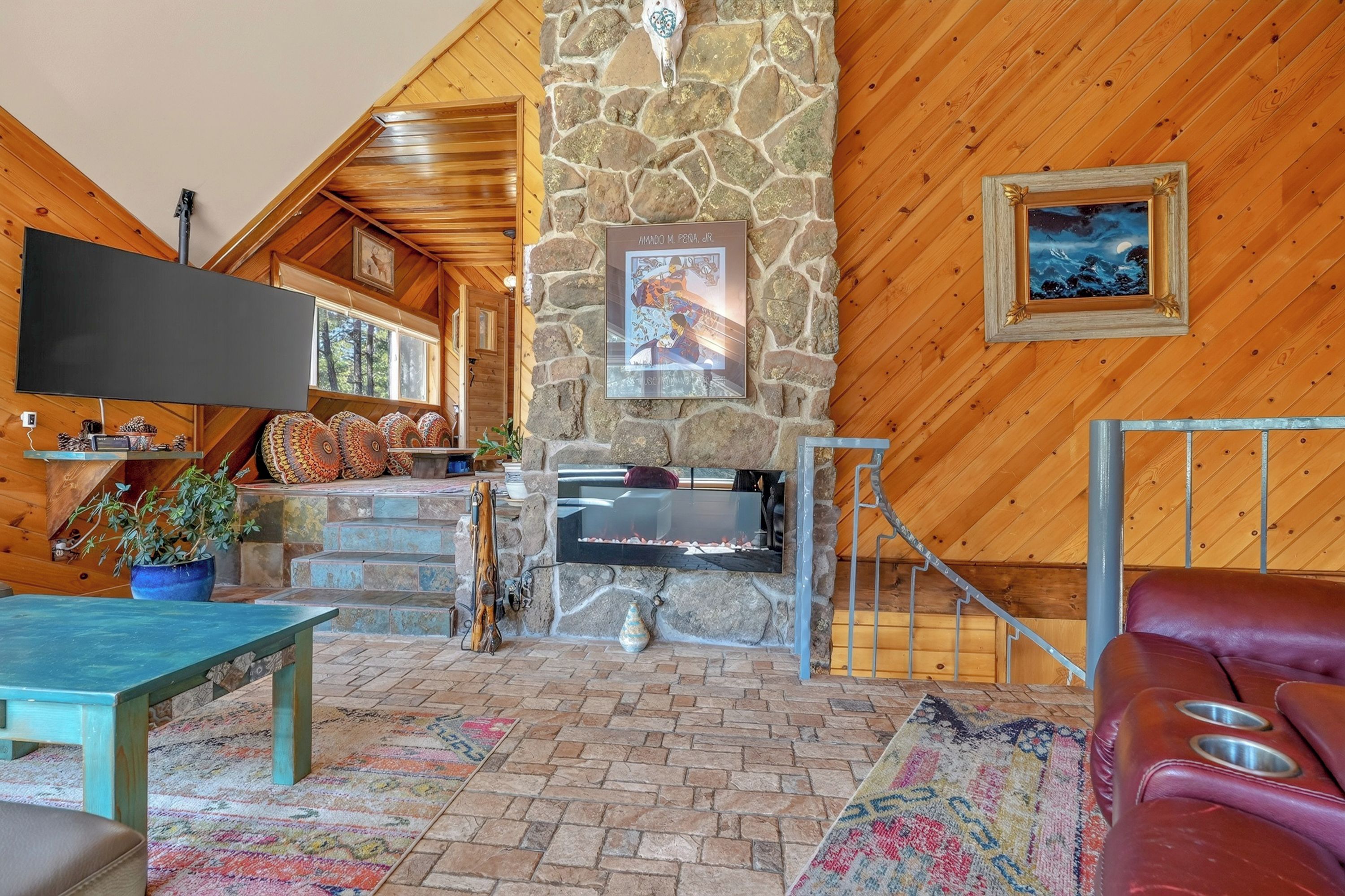 Un interior acogedor con chimenea de piedra, un televisor de pantalla plana y una zona de estar confortable.
