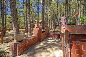 A rustic outdoor area with a brick barbecue and a large planter. - House of Stone and Light: Your Four-Season Sanctuary in Angel Fire, New Mexico (Angel Fire)