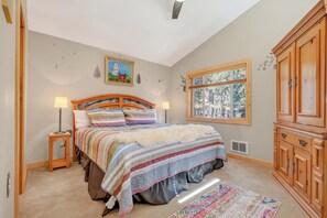 A bedroom with a bed, two bedside lamps, a painting, a window, and a wardrobe. - House of Stone and Light: Your Four-Season Sanctuary in Angel Fire, New Mexico (Angel Fire)