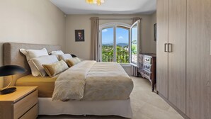 A bedroom with a large bed, bedside tables, a dresser, and a view of a balcony. - Melinda - Super Cannes (Vallauris)