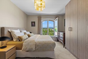 Een slaapkamer met een groot bed, nachtkastjes, een dressoir en uitzicht op een balkon.