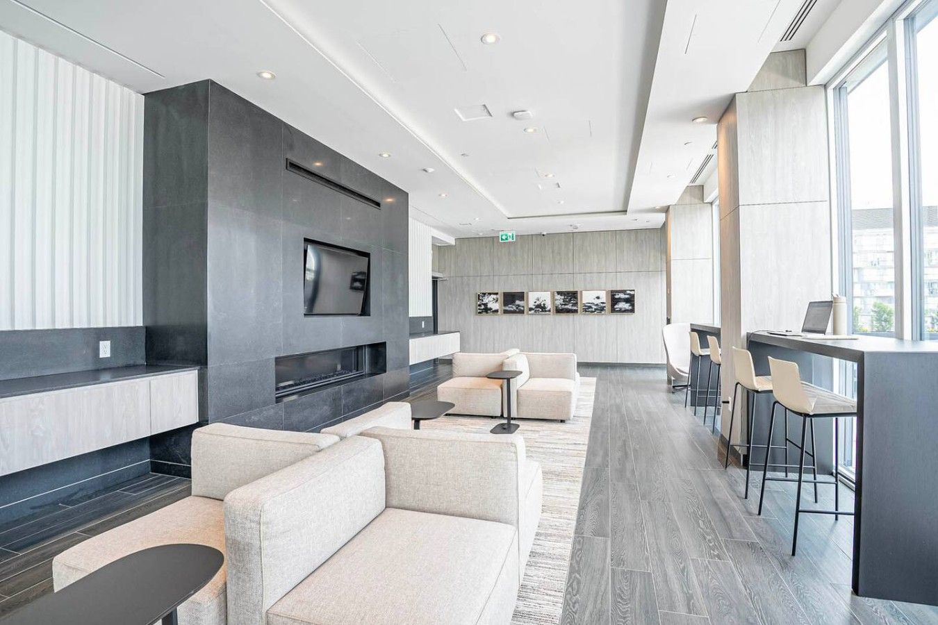 A modern lounge area with sofas, a flat-screen TV, a fireplace, and a bar area with stools.