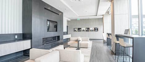 Uma área de estar moderna com sofás, televisão de tela plana, lareira e um bar com banquetas.