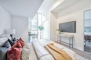 A modern bedroom with a bed, a TV, and a desk. - Luxury King West Suite | 2BR + 2BA | Gym (Toronto)