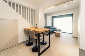 A modern interior with a staircase, a dining area with a table and chairs, a sofa, and a round coffee table. - A Cube Villa - Two Bedroom Villa, Sleeps 5 (Keri)