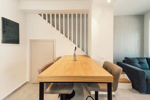 A modern living space with a wooden dining table, a staircase, and a sofa. - A Cube Villa - Two Bedroom Villa, Sleeps 5 (Keri)