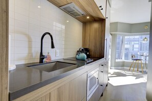 Eine moderne Küche mit einem schwarzen Wasserhahn, einem Wasserkocher und einer Kaffeemaschine auf der Arbeitsfläche.