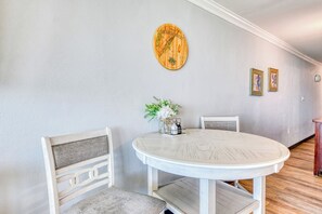A dining area with a round table, two chairs, a decorative wall piece, and a vase with flowers. - Royal Garden Resort 812 - Two Bedroom, Two Bath Oceanfront Condo (Garden City Beach)