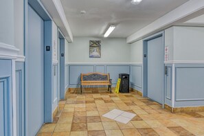 A hallway with a bench, doors, and a trash bin. - Royal Garden Resort 812 - Two Bedroom, Two Bath Oceanfront Condo (Garden City Beach)