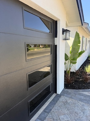 A modern exterior with a grey garage door, a black lantern, and a plant.