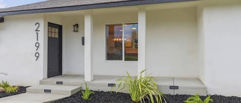 A modern two-story house with a black front door, a small porch, and a number '2199' on the wall.