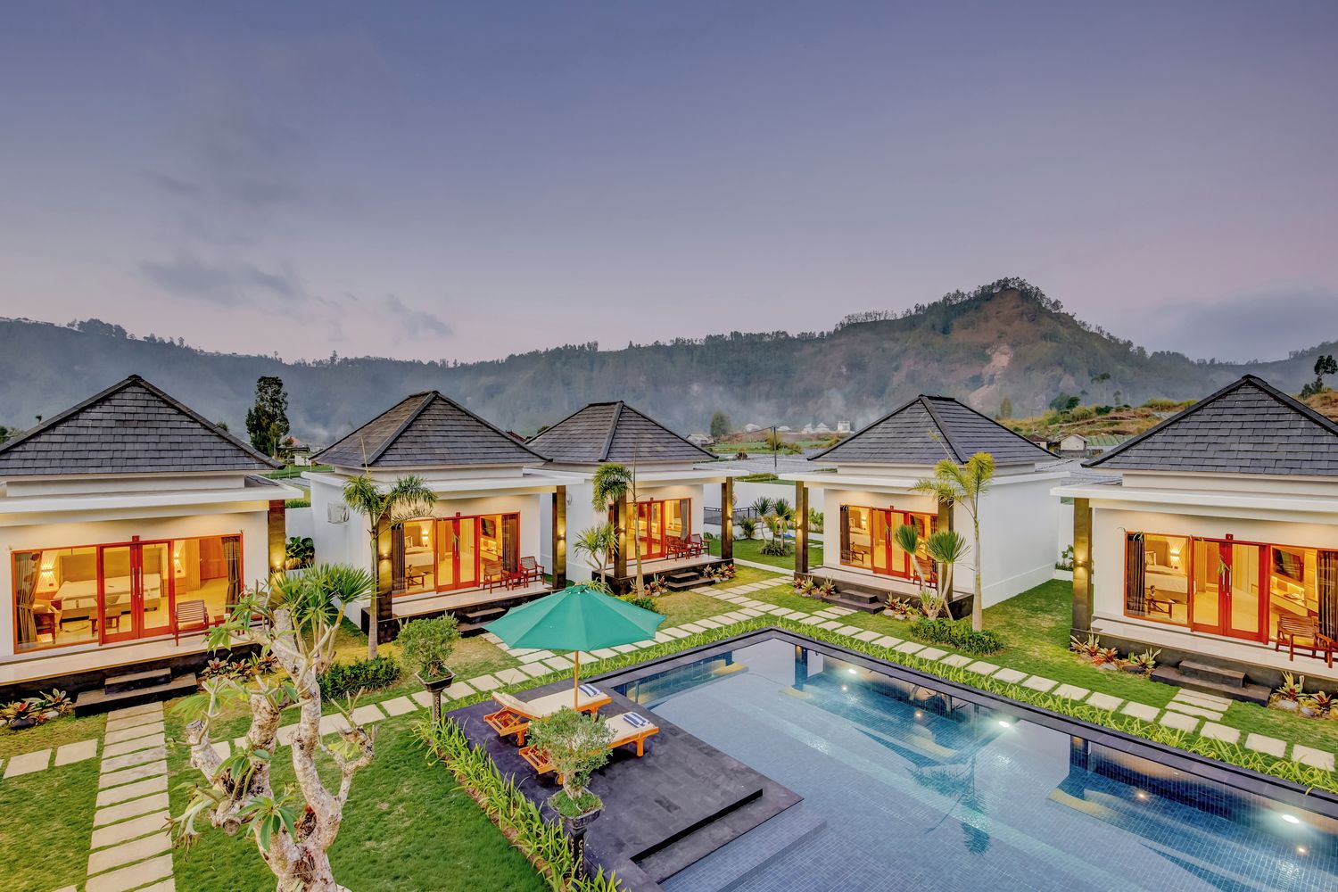 Un resort con varias villas, una piscina y un telón de fondo montañoso.