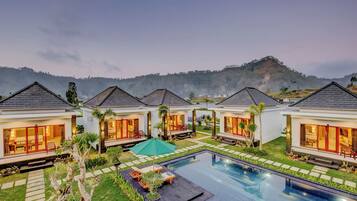 Un resort con varias villas, una piscina y un telón de fondo montañoso.