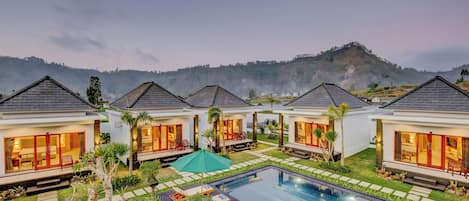 Un complexe hôtelier comprenant plusieurs villas, une piscine et un paysage montagneux en toile de fond.