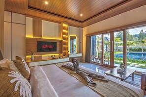 En moderne stue med et stort fladskærms-tv, en sofa, et sofabord og udsigt til en swimmingpool.