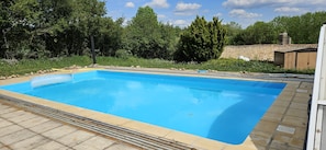 En rektangulær swimmingpool med fliseterrasse hele vejen rundt.