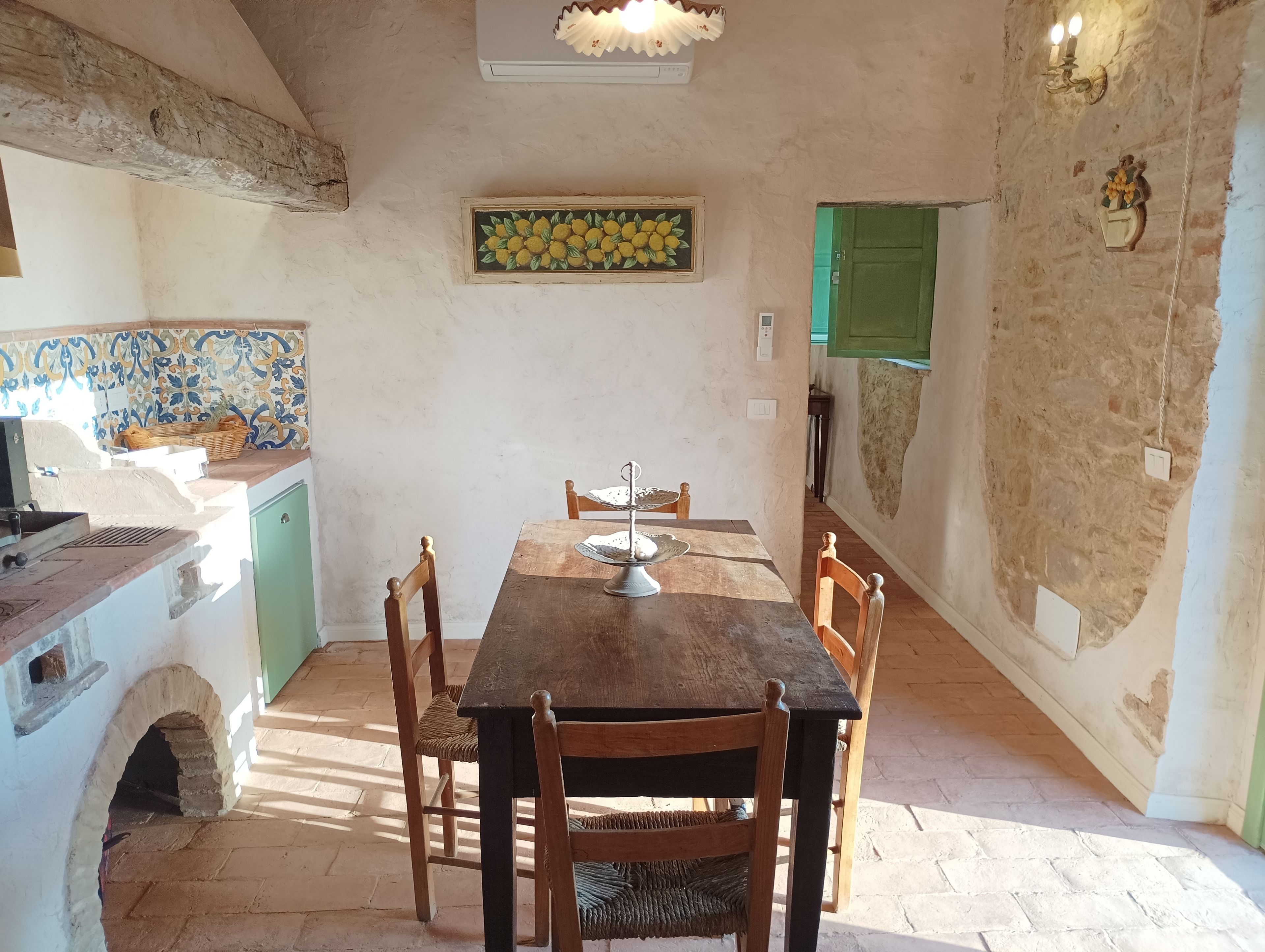 Ein rustikaler Essbereich mit Holztisch und -stühlen, einer gefliesten Spritzschutzleiste und einem grünen Schrank.
