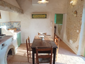 Ein rustikaler Essbereich mit Holztisch und -stühlen, einer gefliesten Spritzschutzleiste und einem grünen Schrank.