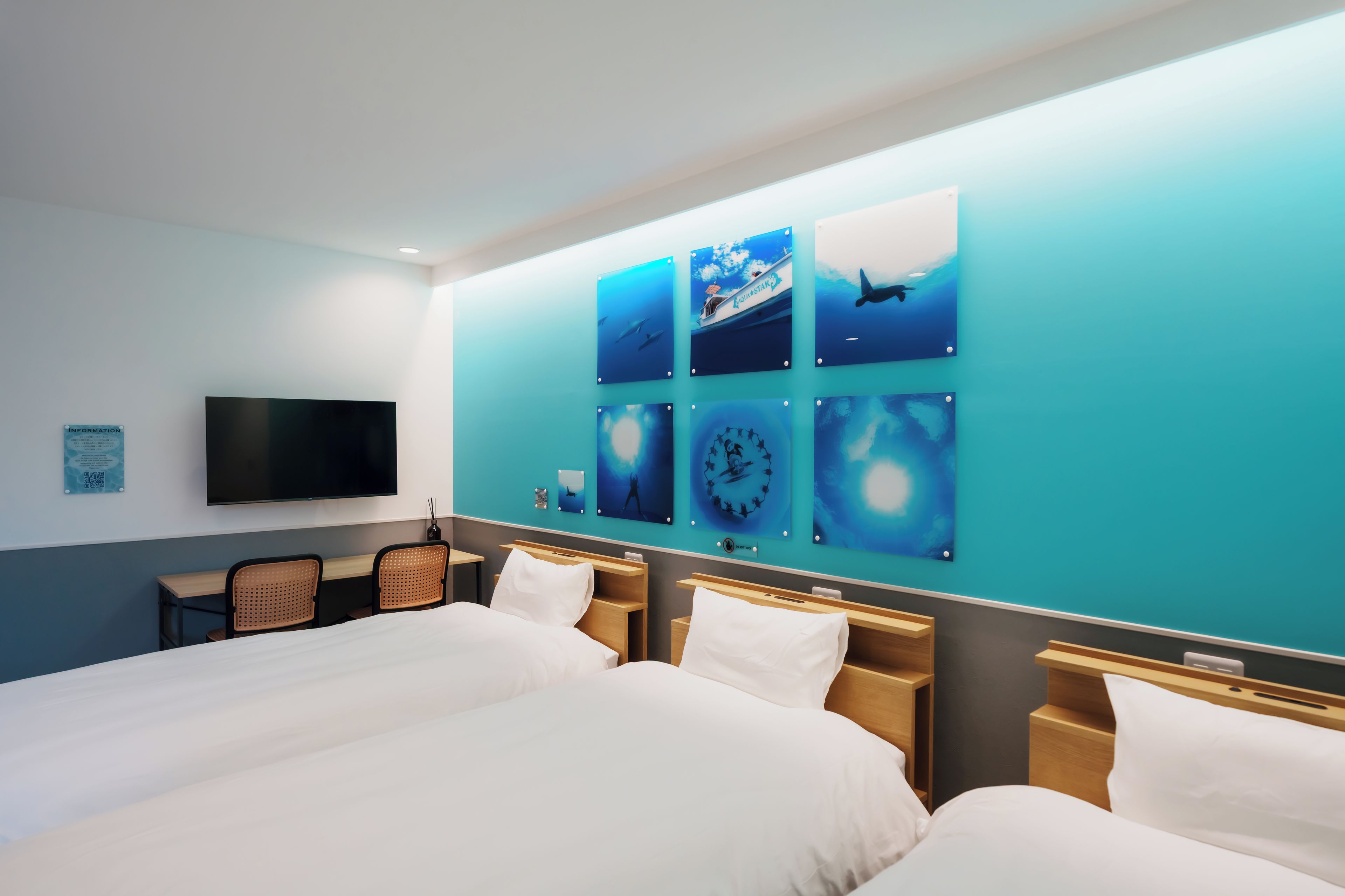 A hotel room with a large bed, a flat-screen TV, and a wall decorated with ocean-themed artwork.