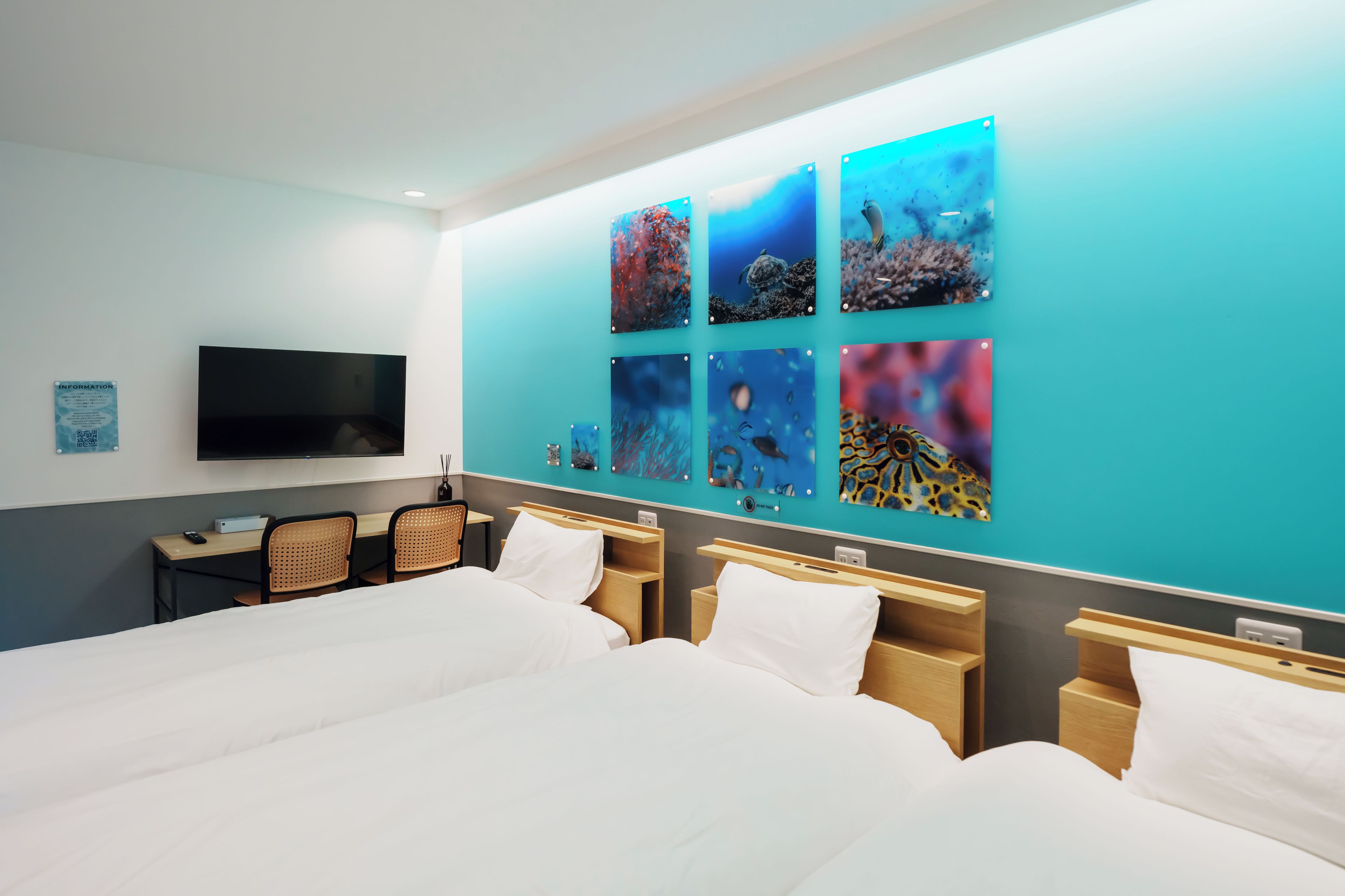 A hotel room with a large bed, a desk with a chair, and a wall-mounted TV.