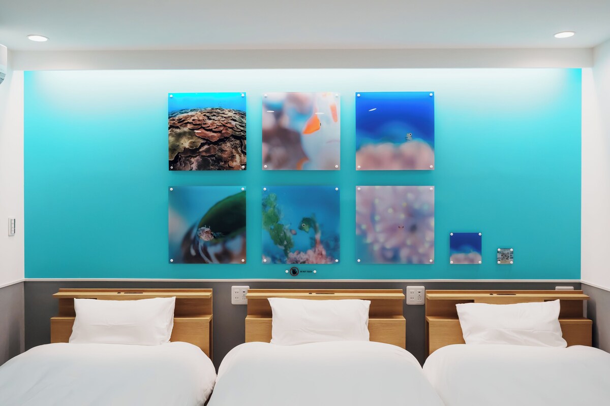 A hotel room with a bed, a wall-mounted artwork display, and a control panel.