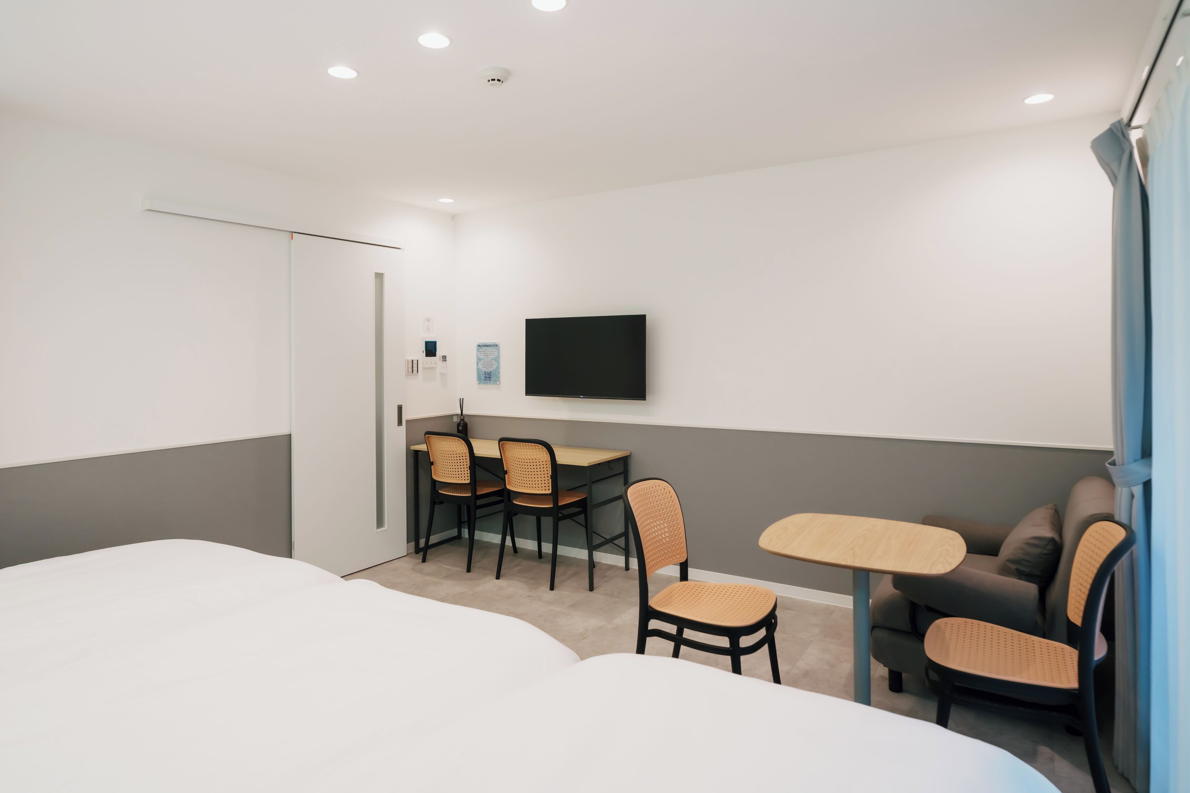 A hotel room with a bed, a desk with chairs, a television, and a sofa.