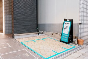 A tiled floor with a blue line marking, a black signboard with QR code, and a tiled wall. - Ocean Blue 9 (Osaka)