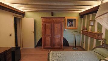 A bedroom with a bed, wooden wardrobe, and a mirror on the wall.