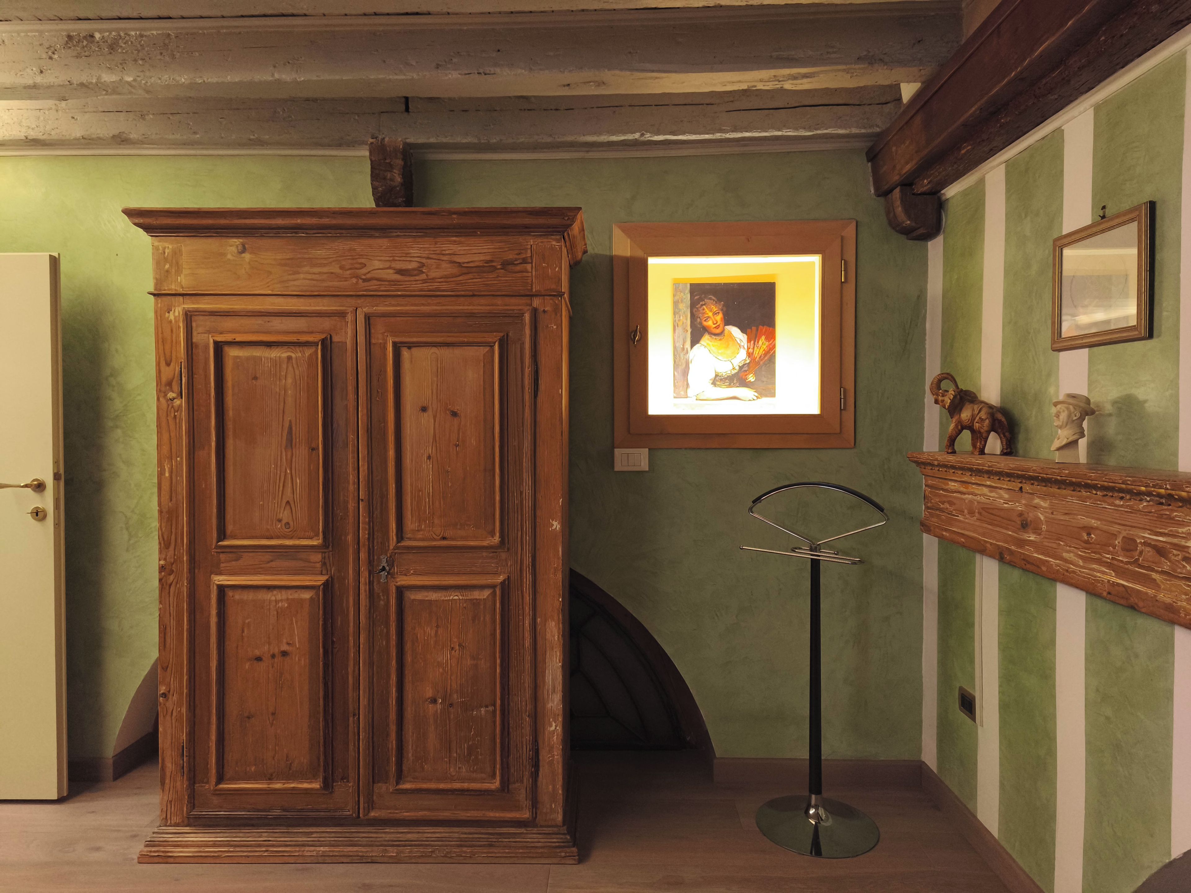 Une pièce avec un meuble en bois, un tableau encadré accroché au mur et un miroir posé sur le sol.