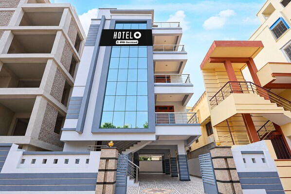 A modern hotel building with a prominent sign, multiple balconies, and a central entrance.