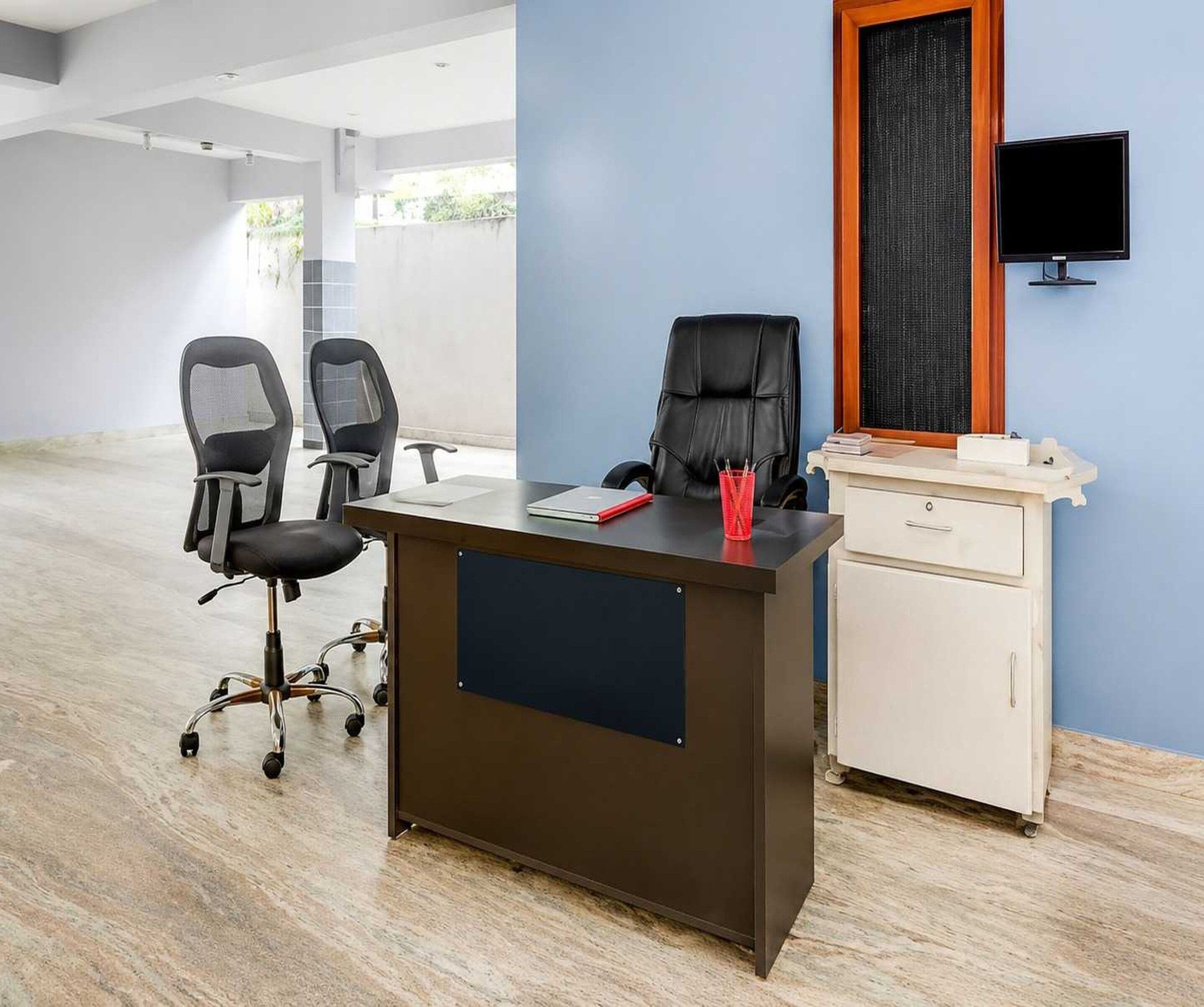 A modern office space with a desk, two office chairs, a computer monitor, and a filing cabinet.