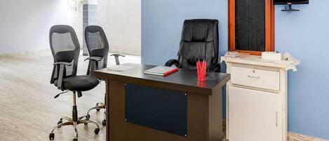 A modern office space with a desk, two office chairs, a computer monitor, and a filing cabinet.