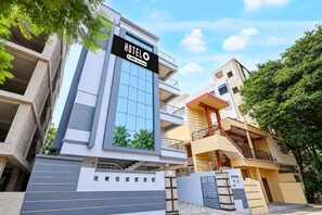 A modern hotel building with a prominent sign, multiple balconies, and a gated entrance.