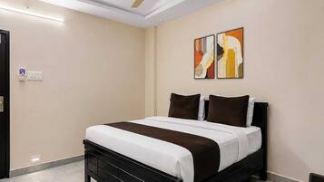 A modern bedroom with a black bed, white bedding, a ceiling fan, and two abstract paintings on the wall.
