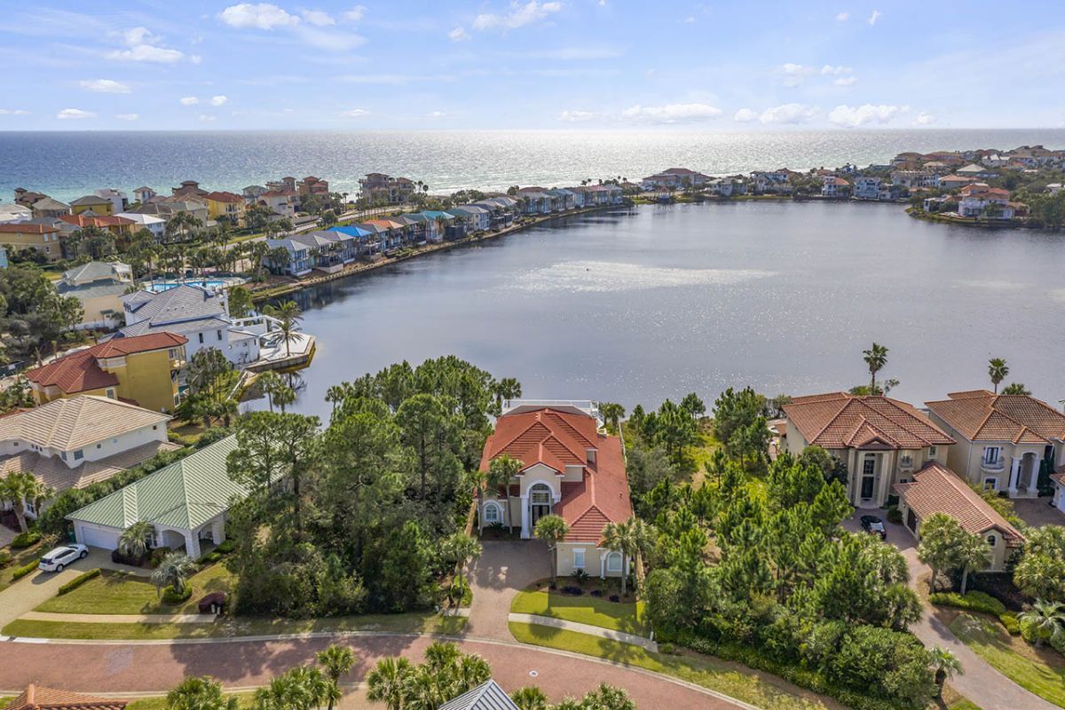 A residential area with houses along a waterfront, featuring a curved road and a clear view of the ocean.