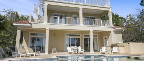 A two-story building with a swimming pool, outdoor seating, and a balcony.