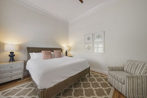 A bedroom with a large bed, two bedside tables with lamps, a patterned rug, and a striped armchair. - Luxury | Rooftop Gulf Views | Private Pool-Spa | 4 King Bedrooms | Sleeps 14 (Destin)