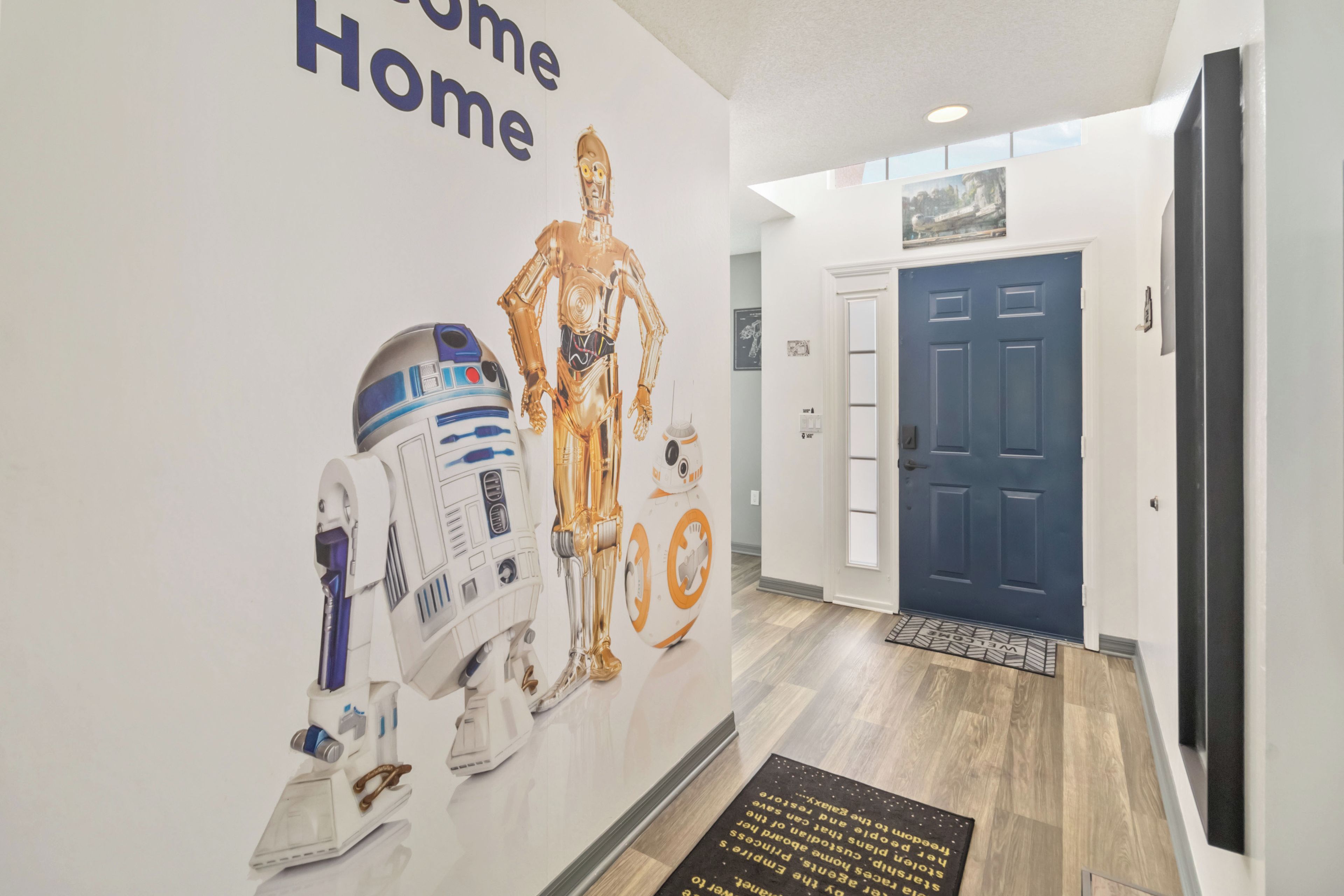 Un pasillo con una pared que muestra personajes de Star Wars y una puerta azul.