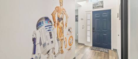 Un pasillo con una pared que muestra personajes de Star Wars y una puerta azul.