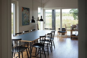 A dining area with a long table, chairs, pendant lights, and a view of the outdoors. - Natural plot with a view of Mols Bjerge (Ebeltoft)
