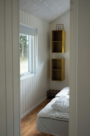 A narrow room with a window, a bed, and two shelves. - Natural plot with a view of Mols Bjerge (Ebeltoft)